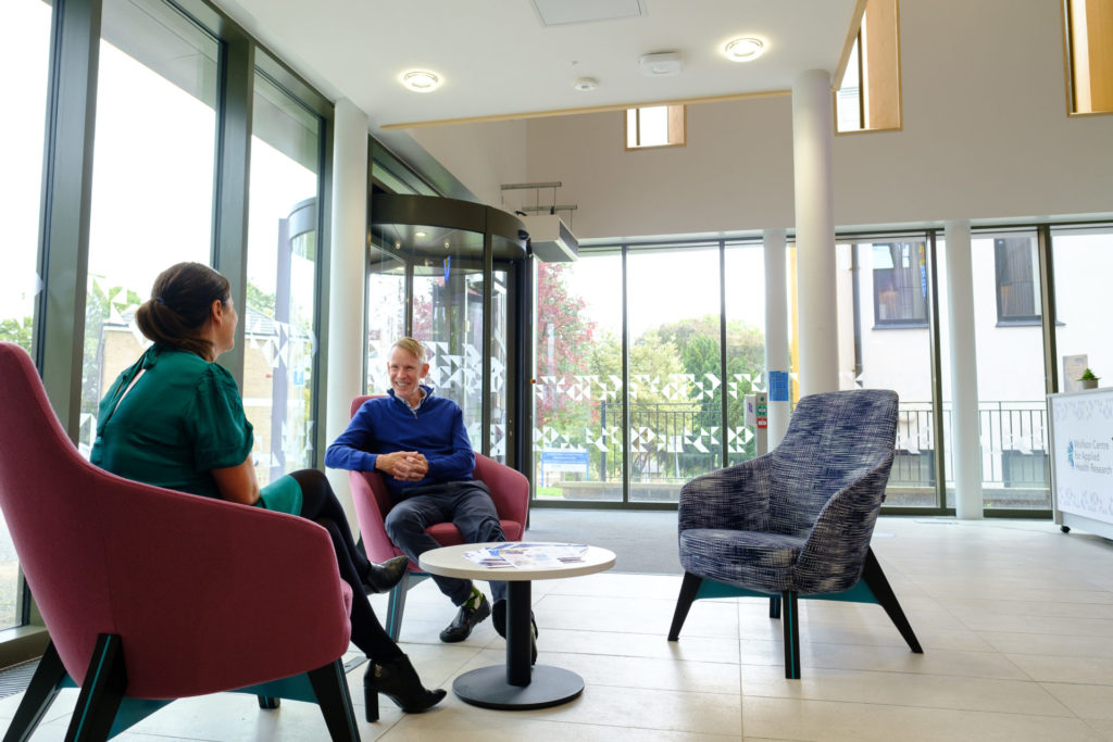 Two people chatting in the reception area of the Wolfson Centre for Applied Health Research